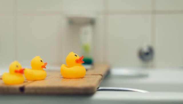 Rubber ducks on a bathtub shelf.
